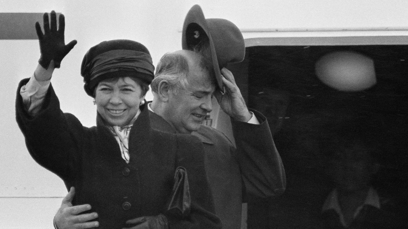 El presidente soviético, Mijáil Gorbachov, y su esposa Raisa, saluda a los reporteros a pesar del viento y la lluvia cuando abordan el Ilyushing-62 al final de una cumbre en Reykjavik el 13 de octubre de 1986. REUTERS/Nick Didlick