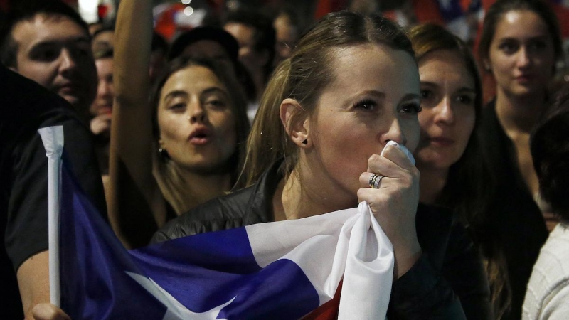 Una mujer besa una bandera chilena mientras personas que rechazan el nuevo proyecto de constitución celebran tras conocer los primeros resultados del referéndum, en Santiago, el 4 de septiembre de 2022.