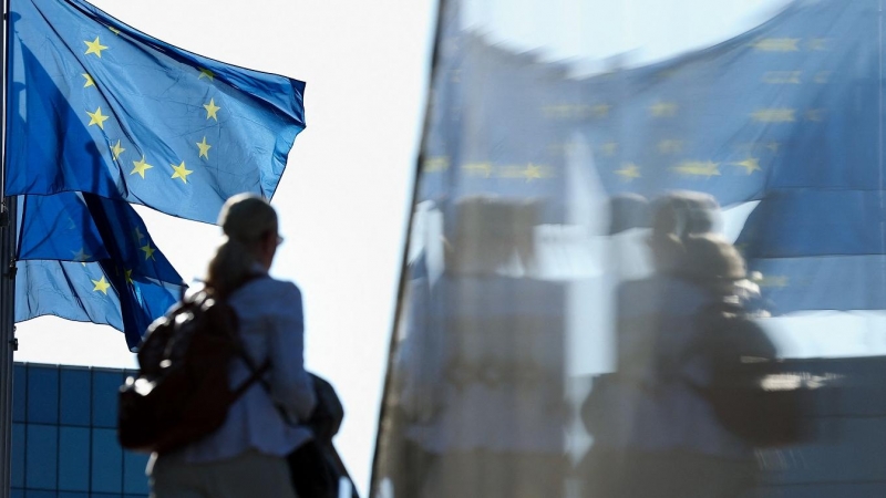 Una mujer pasa junto a las banderas de la UE situadas en el extrerior de la sede de la Comisión Europea, en Bruselas. AFP/Kenzo Tribouillard