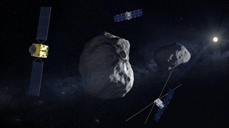 Ilustración de la nave Hera con sus dos pequeños satélites complementarios (Juventas y Milani). Al fondo el sistema doble de los asteroides Dimorphos (el objetivo principal, donde ha impactado la sonda DART de la NASA) y Didymos.