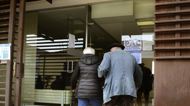 Dos personas mayores entran por la puerta de la residencia.