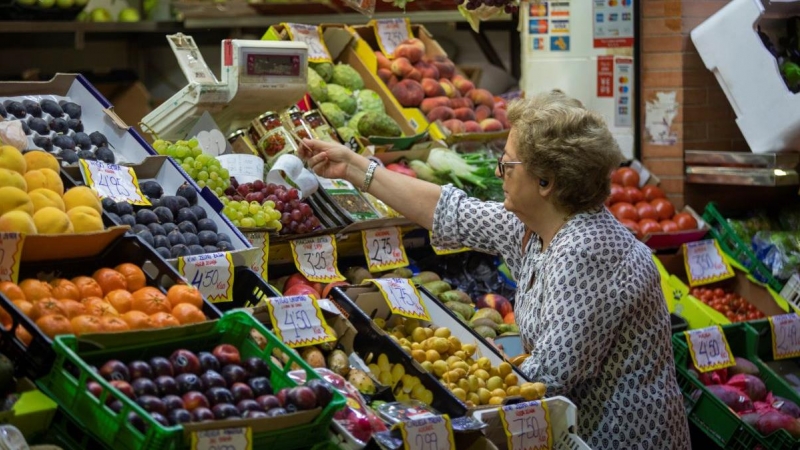 Una mujer compra en uno de los puestos del mercado de abastos de Triana. A 13 de septiembre de 2022, en Sevilla.