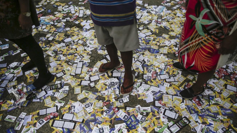 Ciudadanos brasileños esperan (sobre propaganda política) en una fila para votar en un centro de votación hoy, en Río de Janeiro (Brasil).