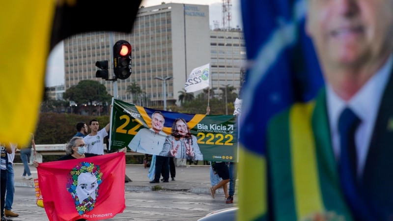 Partidarios del actual presidente Bolsonaro y del exjefe de Estado Lula da Silva promocionan a sus candidatos con banderas y carteles frente a los automovilistas en un semáforo en rojo