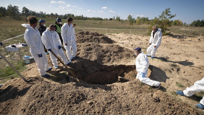 Técnicos forenses trabajan en un lugar de entierro cerca de la ciudad recientemente recuperada de Lyman, en la región de Donetsk.