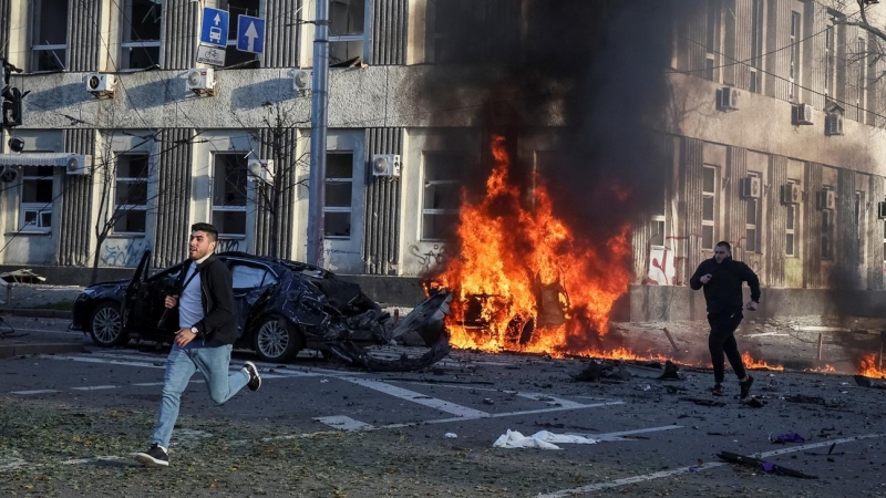 Dos personas corren mientras arden varios coches después de un ataque militar ruso con misiles en el centro de Kiev, la capital de Ucrania, este 10 de octubre de 2022.
