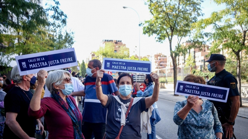 Tres mujeres muestran pancartas en las que figura una placa para la Calle Maestra Justa Freire, en una manifestación para que su nombre vuelva a la que hoy es la calle General Millán-Astray.