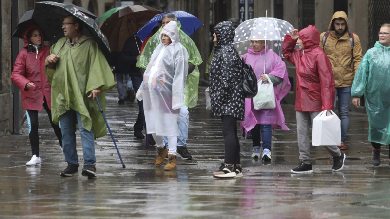 Turistas y peregrinos se protegen de la lluvia en Santiago de Compostela, este jueves.