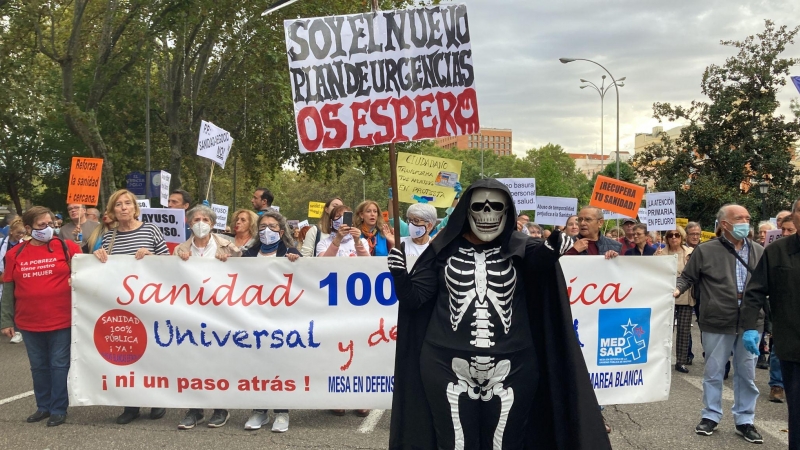 Una persona disfrazada de calavera sostiene una pancarta en la manifestación en Madrid contra la gestión sanitaria del Gobierno de Ayuso