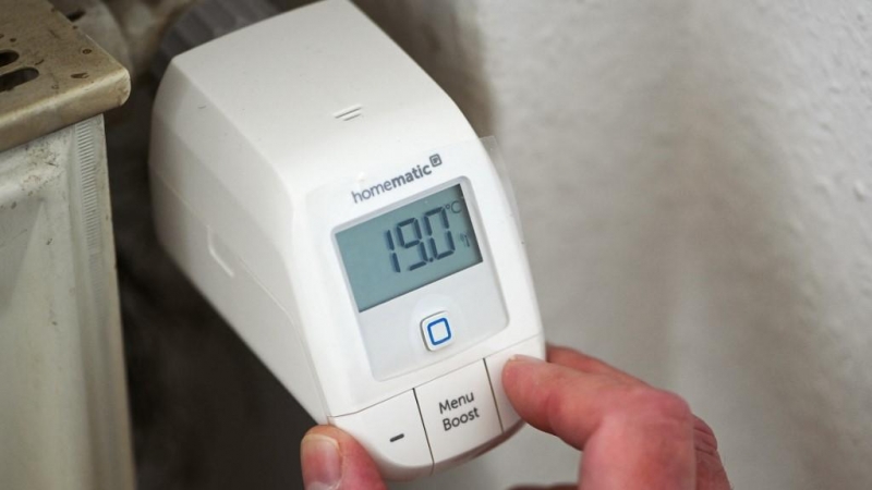 Una persona ajusta el termostato de un radiador.