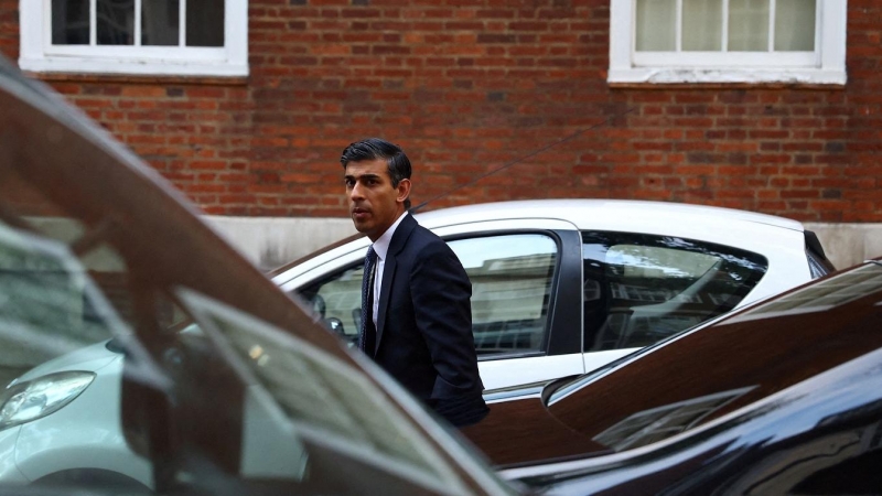 El próximo primer ministro británico, Rishi Sunak, pasa entre varios vehículos cuando se dirige a la sede del Partido Conservador, momentos antes de ser designado como nuevo líder de la formación. REUTERS/Hannah McKay