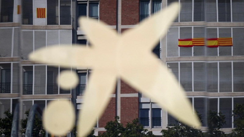 El logo de Caixabank, reflejado en una ventana de su sede en Barcelona. REUTERS/Albert Gea