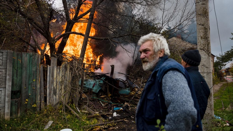 Varios residentes se paran cerca de una estructura en llamas después de un bombardeo en la ciudad de Bakhmut, en la región del Donbás, en el este de Ucrania, el 23 de octubre de 2022.