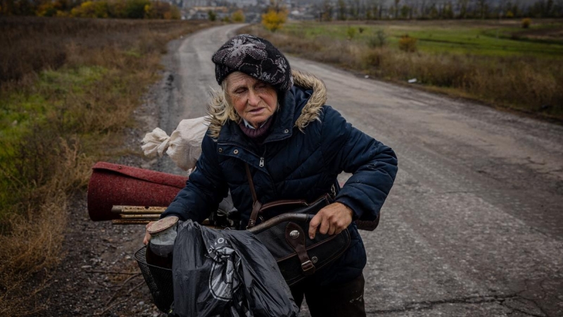 Una anciana empuja su bicicleta cuando sale de la ciudad de Bakhmut, ubicada en la región industrial del Donbás, en el este de Ucrania, el 23 de octubre de 2022.