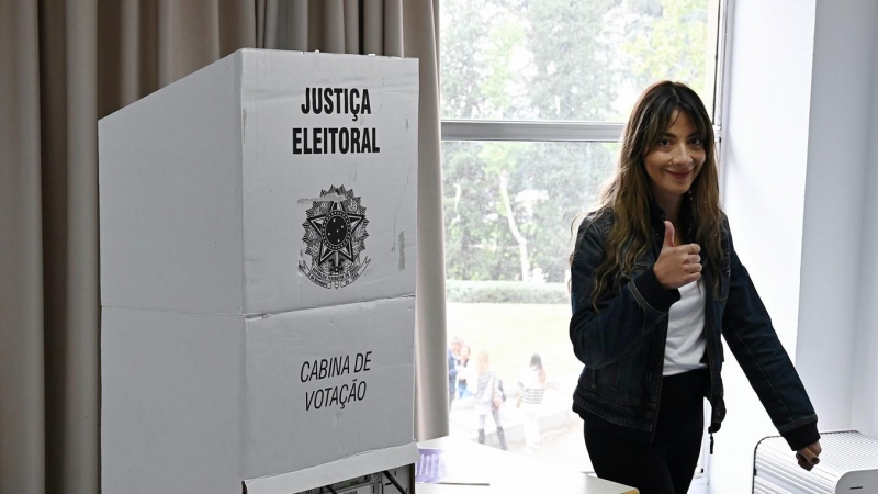 Una joven al lado de una urna para ejercer el voto en Brasil.