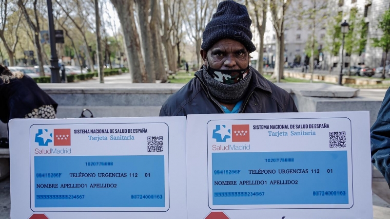 Un manifestante porta un cartel durante una concentración en la que se ha entregado un manifiesto al Ministerio de Sanidad contra la exclusión sanitaria, frente al Ministerio de Sanidad, a 7 de abril de 2022, en Madrid (España).