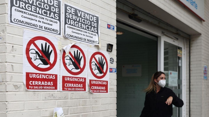 Una sanitaria con mascarilla en la puerta del Centro de Salud Ángela Uriarte, donde hay carteles de protesta que rezan 'Urgencias Cerradas, tu salud vendida', a 21 de octubre de 2022, en Madrid.