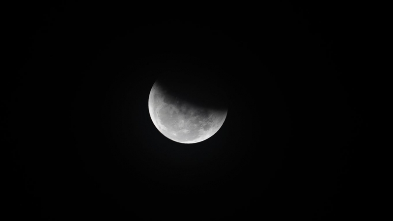 08-11-22 Un eclipse lunar total visto en medio del cielo nublado en Katmandú, Nepal.