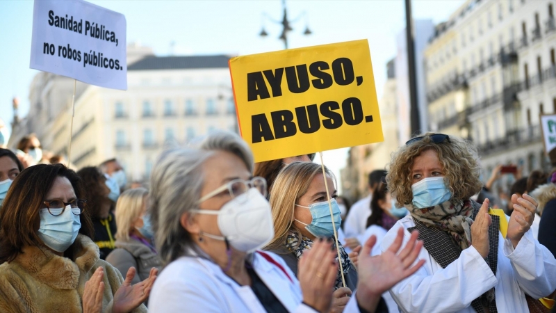 Un grupo de personas con un cartel donde se puede 'Ayuso, abuso' en una concentración en defensa de la Atención Primaria, a 13 de noviembre de 2021, en Madrid, (España).