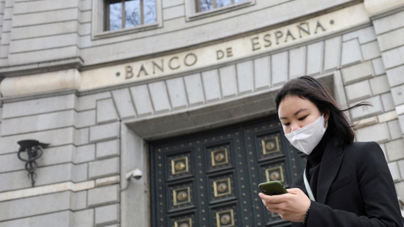 Una joven con mascarilla delante de la entrada del edificio del Banco de España en Barcelona. REUTERS/Nacho Doce