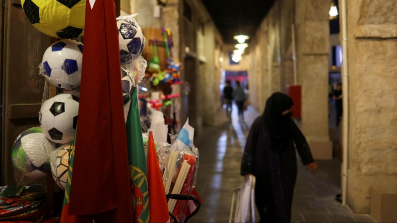 Una mujer camina, con el hiyab, por una calle de Catar decorada con banderas por el Mundial.