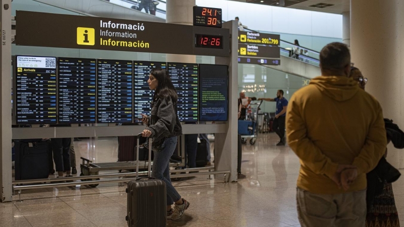 Varias personas observan un panel de llegadas en el aeropuerto de Barcelona-El Prat. E.P./Lorena Sopêna