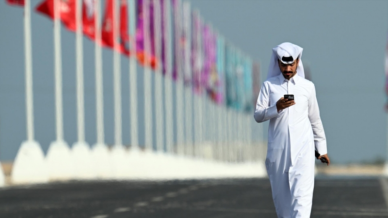 Un hombre pasea junto a las banderas de las selecciones que participan en el Mundial de fútbol de Catar