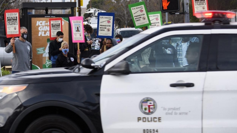Un coche de la Policía de Los Ángeles pasa junto a una protesta por las muertes de George Floyd y Daunte Wright, a 12 de abril de 2021.