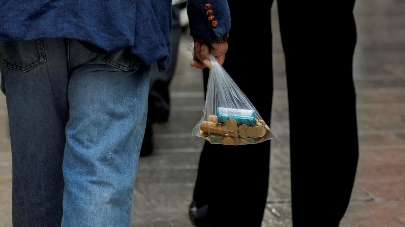 un hombre lleva una bolsa con monedas, en Ronda (Málaga). REUTERS/Jon Nazca