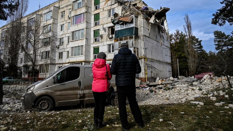 02/12/2022 Dos personas residentes en la zona observan los daños en un bloque de viviendas bombardeado en la ciudad ucraniana de Kluhyno-Bashkyrivka (Járkov)