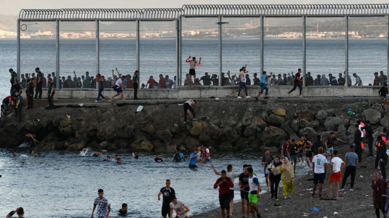 Personas migrantes caminan por la playa del Tarajal, el 17 de mayo de 2021, en Ceuta. E.P./Antonio Sempere