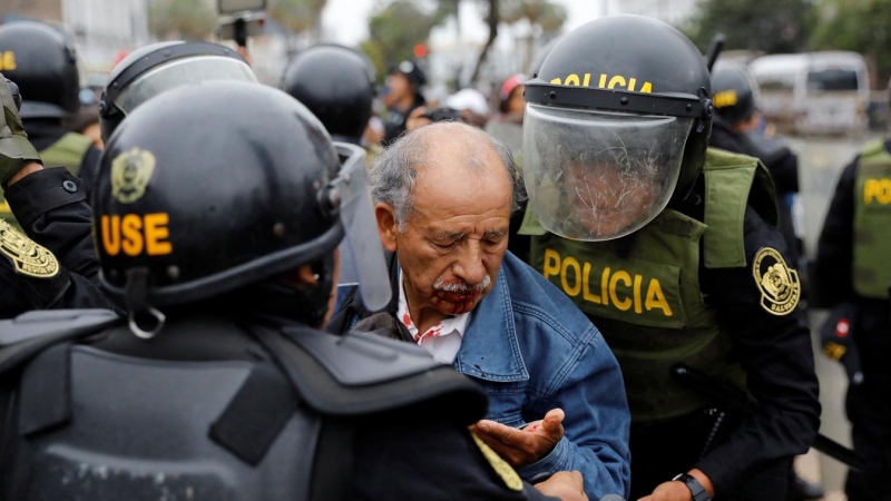 Un manifestante herido entre los agentes de policía apostados fuera de la Prefectura de Lima, mientras declaraba el presidente destituido Pedro Castillo. REUTERS/Alessandro Cinque