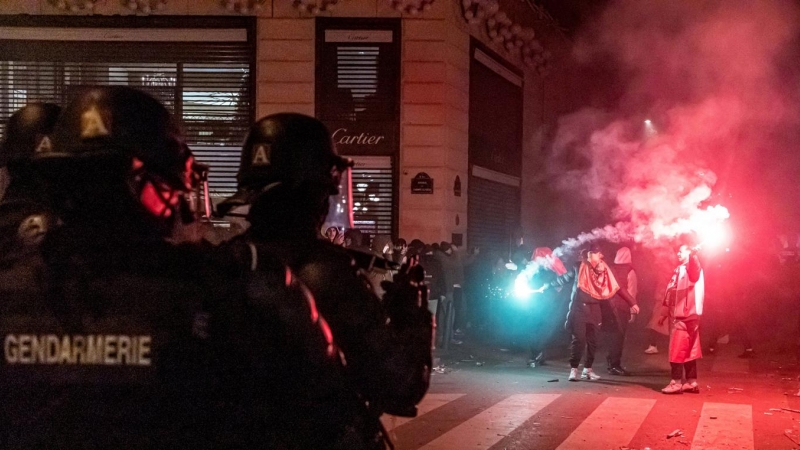 Agentes de policía montan guardia mientras los aficionados franceses y marroquíes celebran que sus equipos ganaran la Copa Mundial de la FIFA 2022.