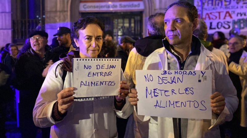 Dos profesionales sanitarios protestasn después de que la Consejería de Sanidad impida trasladar alimentos a los médicos encerrados en el edificio.