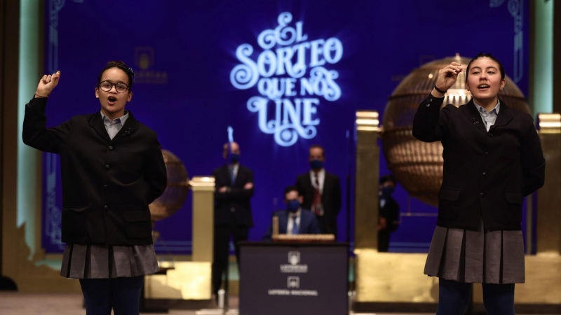 Paula Figuereo y Yanisse Alexandra, dos de las niñas de la residencia de San Ildefonso, posan minutos después de cantar el primer premio 86.148, durante la celebración del Sorteo Extraordinario de la Lotería de Navidad 2021 en el Teatro Real de Madrid, a