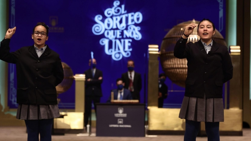 Paula Figuereo y Yanisse Alexandra, dos de las niñas de la residencia de San Ildefonso, posan minutos después de cantar el primer premio 86.148, durante la celebración del Sorteo Extraordinario de la Lotería de Navidad 2021 en el Teatro Real de Madrid, a