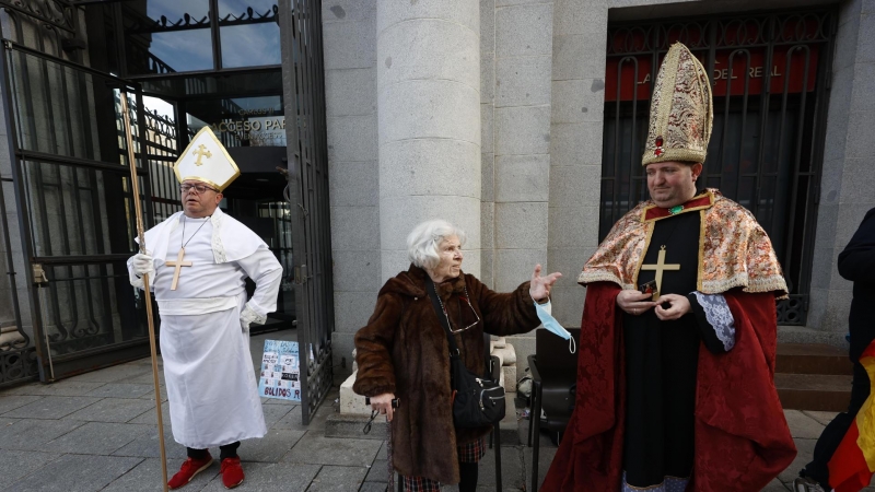 Manoli (c), una anciana de 85 años, acostumbrada a salir en la tele el día del sorteo de la Lotería de Navidad, disfrazada con distintos atuendos, junto a Jesús (d), otro habitual de la cola del sorteo desde hace quince años, disfrazado de Fernando VII, y