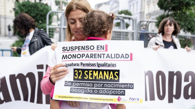 Una mujer sostiene a su hija en brazos durante una concentración de madres solteras, en el Congreso de los Diputados, a 29 de septiembre de 2022, en Madrid.