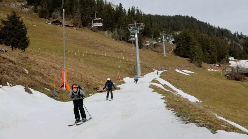 Esquiadores pasan sobre una pequeña capa de nieve en medio de temperaturas invernales más cálidas de lo habitual en los Alpes en Leysin, Suiza, a 4 de enero de 2023