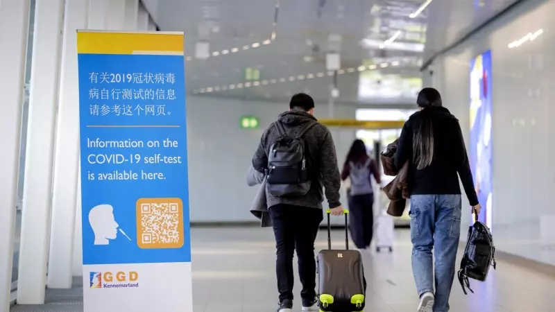 Viajeros de China pasan frente a una pancarta con información y reciben un test de covid-19 a su llegada a Schiphol, Países Bajos, el 04 de enero de 2023.