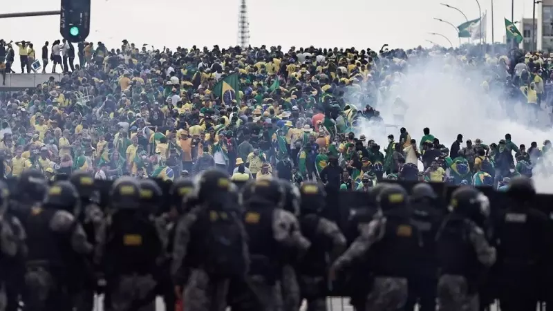 Los policías observan a los miles de seguidores ultras de Bolsonaro que han asaltado el Congreso de Brasil.