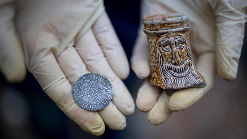 Lara Maiklem, autora del libro ‘Mudlarking’, muestra una moneda del siglo XVII y un trozo de una belarmina en el río Támesis de Londres.