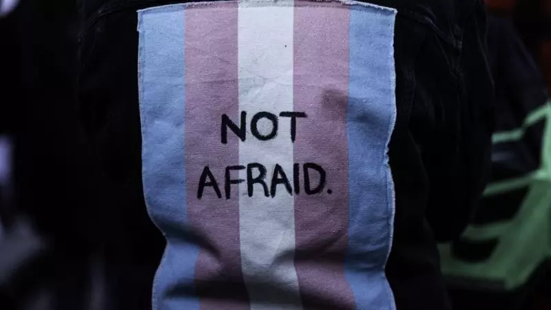 Imagen de archivo de una persona con un chaleco con una bandera trans en la espalda con las palabras 'Sin miedo'