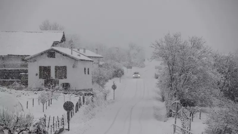 Un vehículo circula por una carretera en Viscarret (Navarra) donde el temporal de lluvia y nieve mantiene la región en alerta naranja.