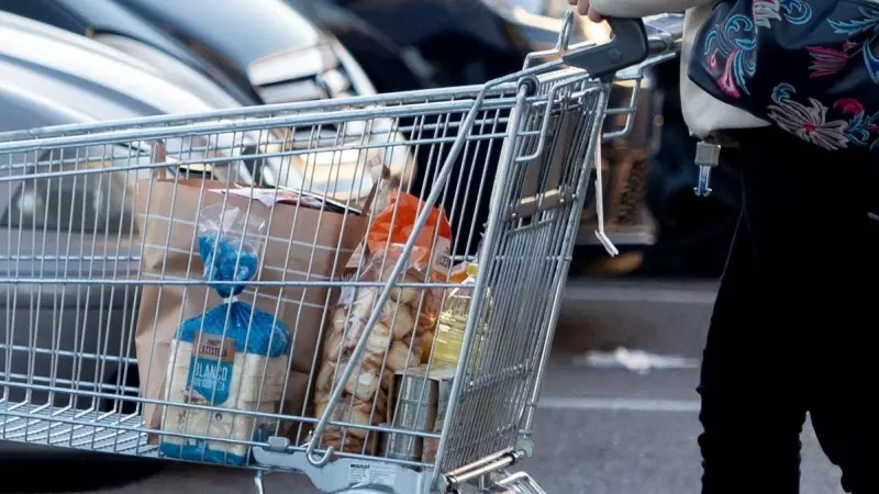 Una mujer sale de un supermercado con un carro de la compra, a 27 de diciembre de 2022, en Mejorada del Campo, Madrid.