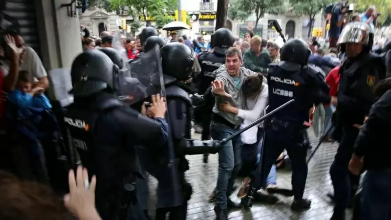 Un hombre intenta proteger a una mujer de los porrazos de agentes antidisturbios de la policía española el 1 de octubre de 2017.