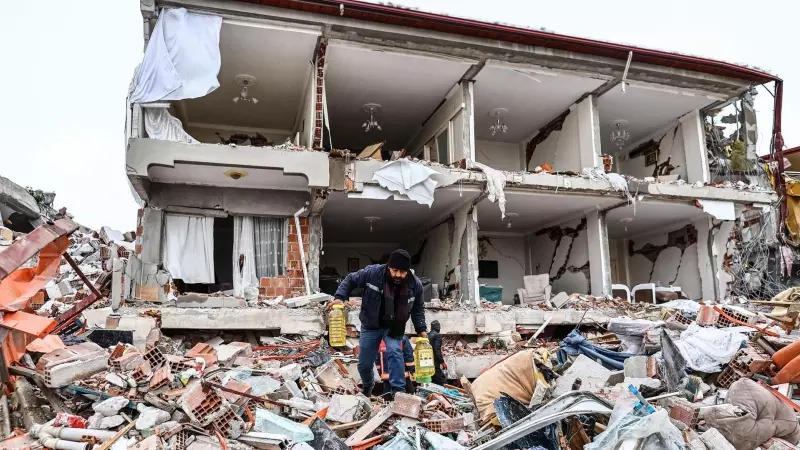 Un hombre carga con botellas de aceite y pasa por los escombros de una casa destrozada por el terremoto en la ciudad turca de Kahramanmaras este 7 de febrero de 2023.