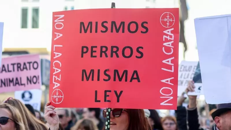 Una mujer porta una pancarta con el lema 'Mismos perros, misma ley' durante una manifestación contra la caza en Madrid.