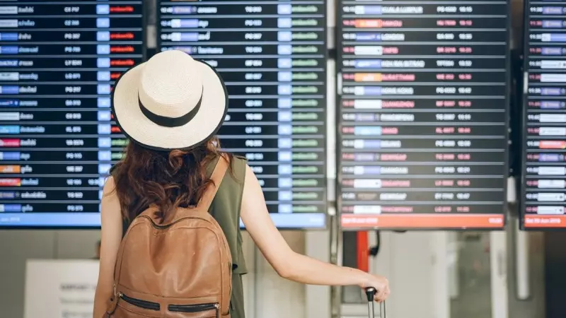 Una viajera consultando el panel de vuelos en un aeropuerto.