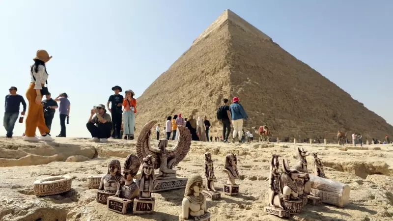 Pequeñas figuritas 'souvenirs' descansan en el suelo junto a las pirámides de Guiza ante los ojos de decenas de turistas este 2 de marzo de 2023.
